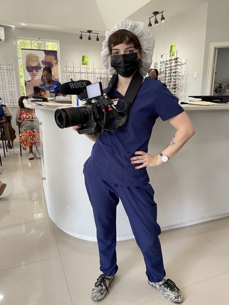 McKenzie holding a cinema camera in scrubs on a themed set