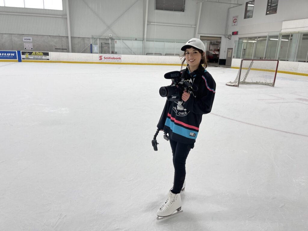 McKenzie filming with a handheld camera on an ice rink